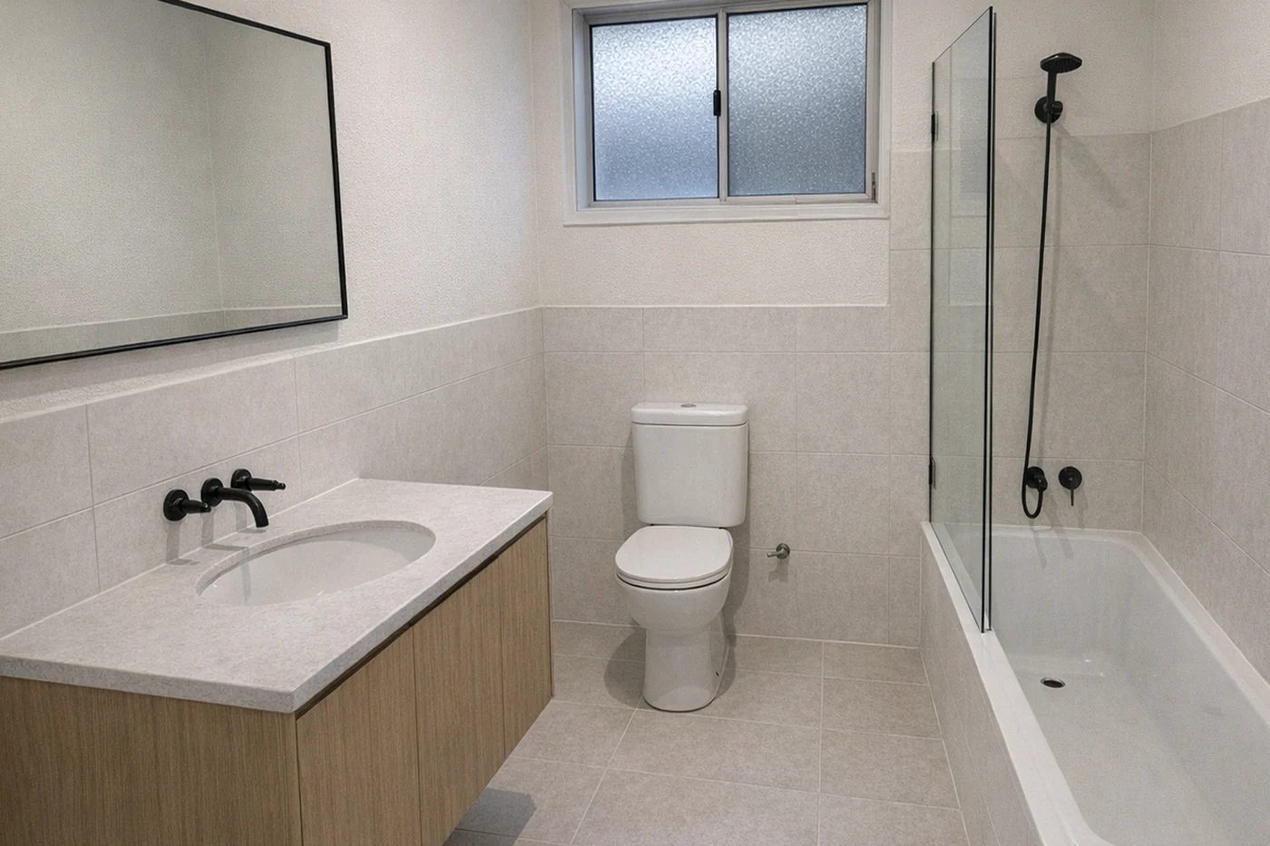 The same bathroom renovated, with new tiling, vanity, shower screen and tapware