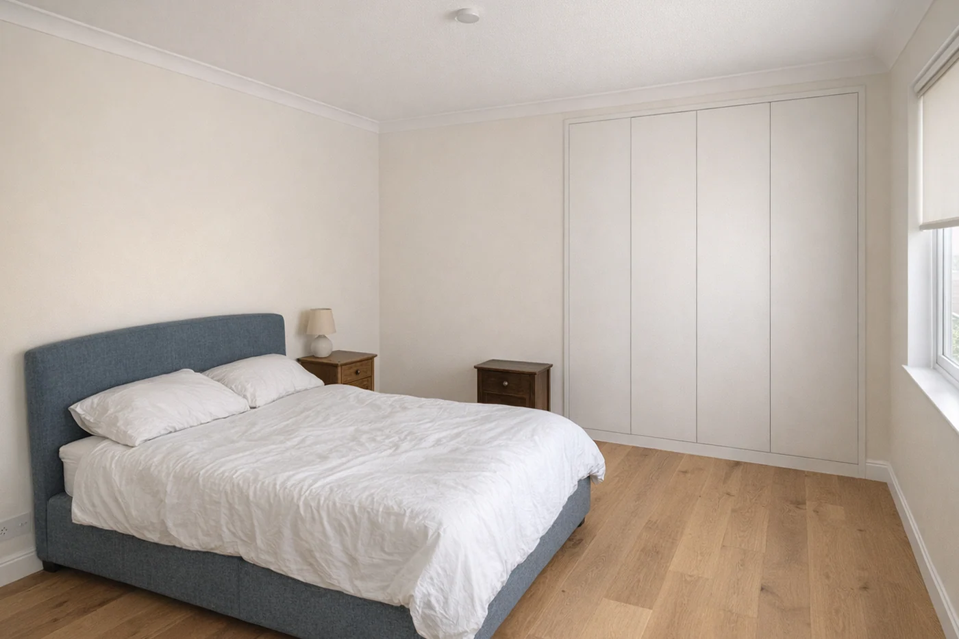The same bedroom renovated, with a new floor, repainted walls and a built-in robe — the bed, bedside tables and lamp unchanged